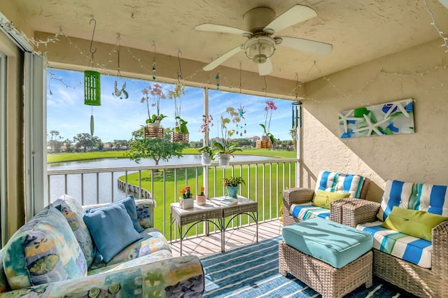 sunroom / solarium featuring ceiling fan and a water view