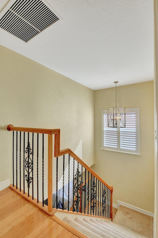 staircase featuring an inviting chandelier and hardwood / wood-style flooring