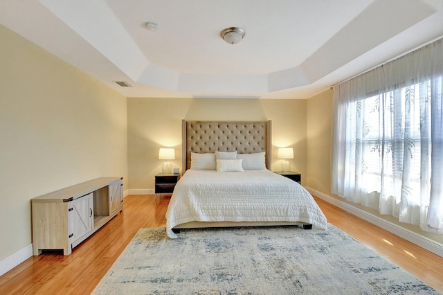 bedroom featuring light hardwood / wood-style flooring and a tray ceiling