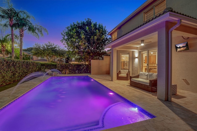 pool at dusk with a patio and pool water feature