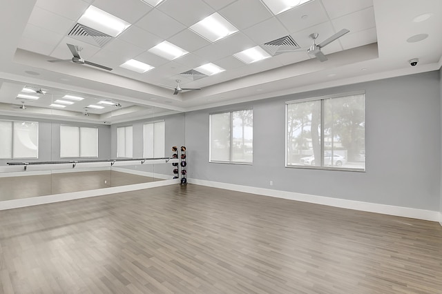 exercise area with ceiling fan, a tray ceiling, a drop ceiling, and hardwood / wood-style floors