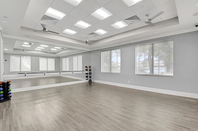 workout room with wood-type flooring, ceiling fan, a raised ceiling, and a paneled ceiling