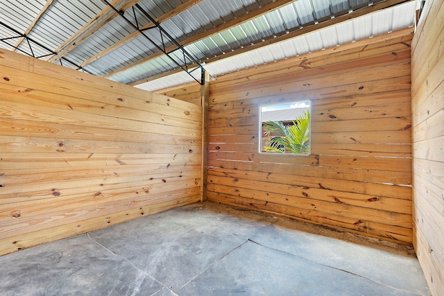 empty room featuring concrete floors and wood walls