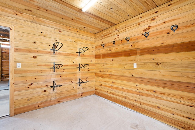 unfurnished room with wooden walls, concrete floors, and wooden ceiling