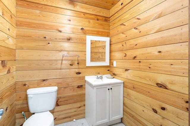 bathroom with vanity, wood walls, and toilet