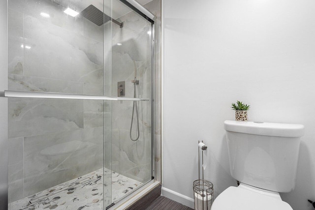 bathroom featuring toilet and a shower with door