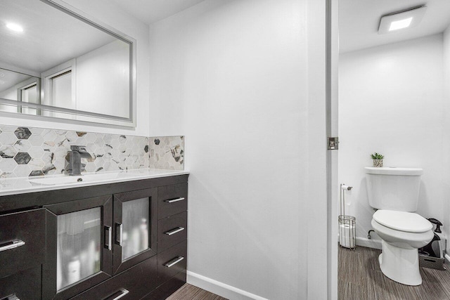 bathroom featuring hardwood / wood-style floors, decorative backsplash, toilet, and vanity