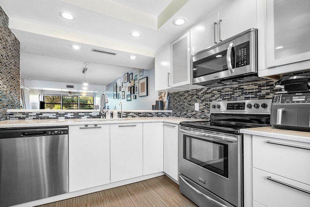 kitchen featuring white cabinets, sink, stainless steel appliances, and tasteful backsplash