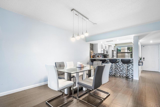 dining room with wood-type flooring, a textured ceiling, and track lighting