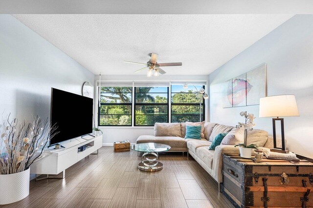 living room with ceiling fan, dark hardwood / wood-style flooring, and a textured ceiling