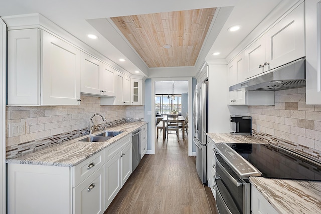 kitchen with sink, hardwood / wood-style flooring, appliances with stainless steel finishes, light stone counters, and white cabinetry