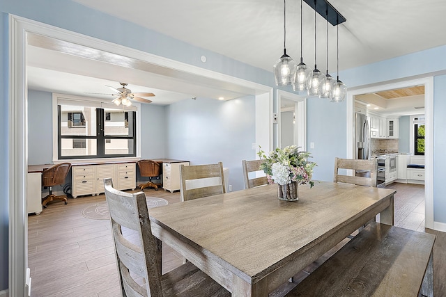 dining space featuring wood-type flooring, built in desk, and ceiling fan