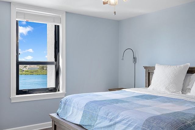 bedroom with ceiling fan and a water view