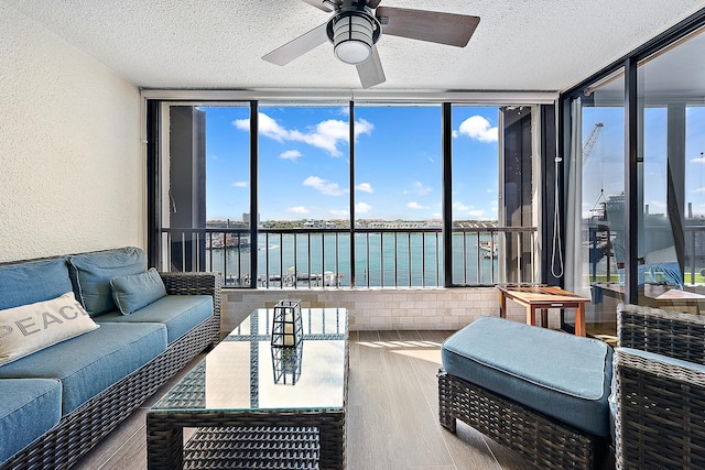 sunroom / solarium featuring ceiling fan, a water view, and a healthy amount of sunlight