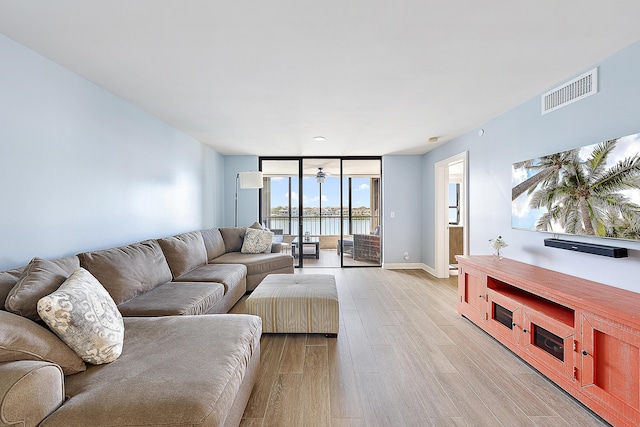 living room with a wealth of natural light, light hardwood / wood-style flooring, and expansive windows