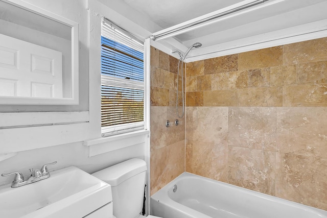 full bathroom featuring tiled shower / bath combo, toilet, and sink