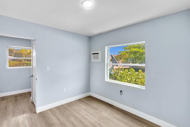 unfurnished room with light wood-type flooring, a wealth of natural light, and a wall mounted AC