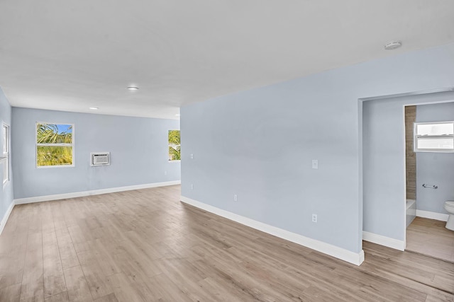 unfurnished room with a wall mounted AC and light hardwood / wood-style flooring