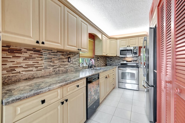 kitchen with backsplash, light stone countertops, stainless steel appliances, a textured ceiling, and sink