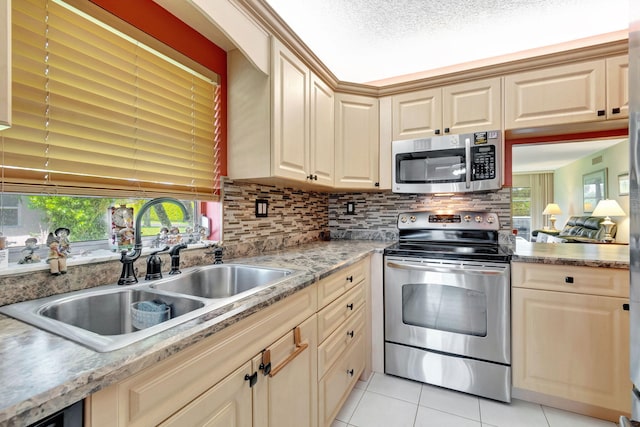 kitchen with appliances with stainless steel finishes, tasteful backsplash, light tile patterned floors, a textured ceiling, and sink