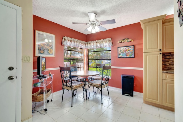 tiled dining space with ceiling fan and a textured ceiling