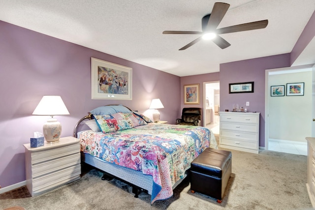 bedroom featuring ensuite bath, ceiling fan, light colored carpet, and a textured ceiling