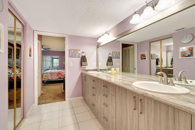 bathroom with vanity, a textured ceiling, tile patterned flooring, and a shower with door