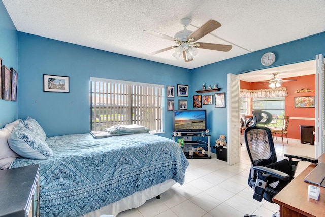 tiled bedroom with ceiling fan and a textured ceiling