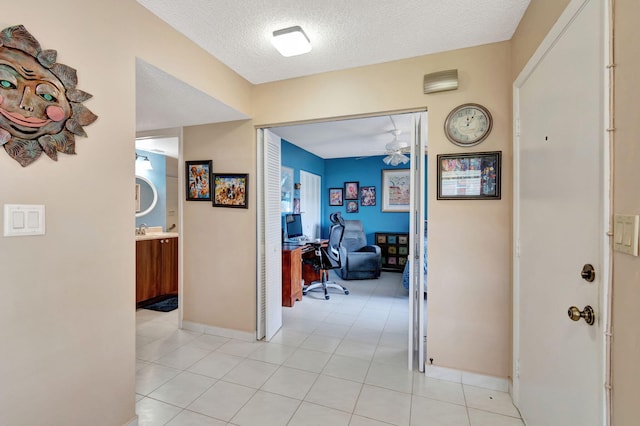 hall featuring a textured ceiling and light tile patterned floors