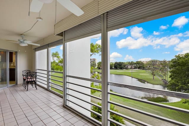 sunroom / solarium with golf course view, plenty of natural light, a water view, and a ceiling fan