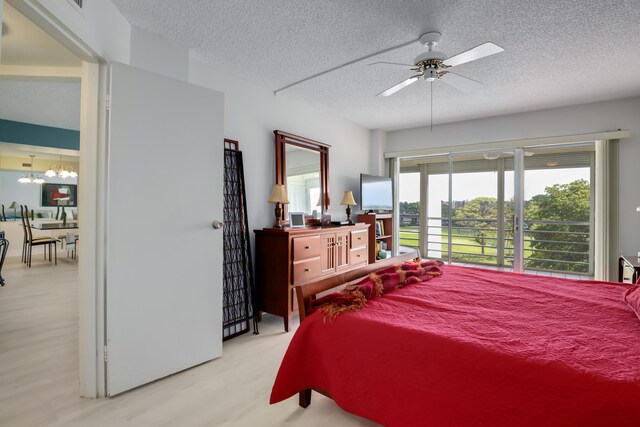bedroom featuring a textured ceiling, light wood finished floors, and ceiling fan with notable chandelier