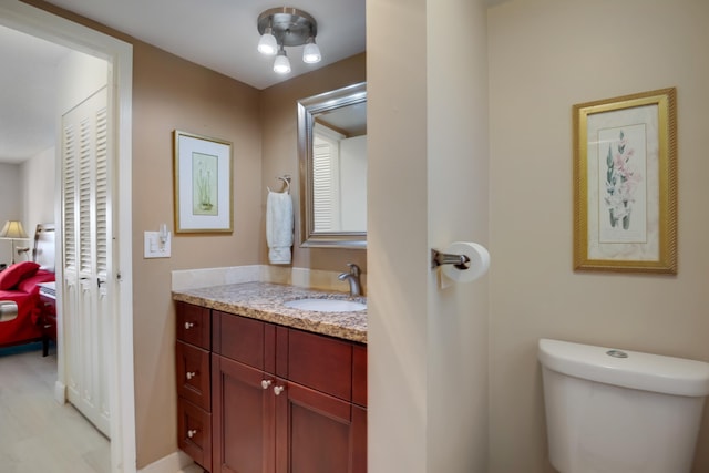 half bathroom featuring baseboards, toilet, and vanity
