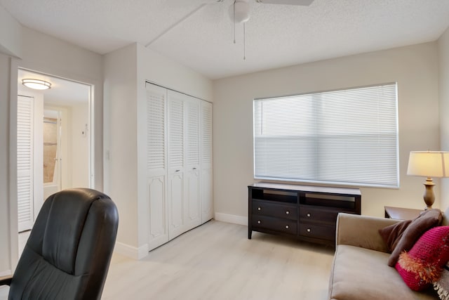 interior space with ceiling fan, a textured ceiling, and light hardwood / wood-style floors