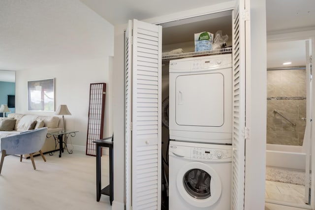 clothes washing area with stacked washer and dryer, baseboards, and laundry area