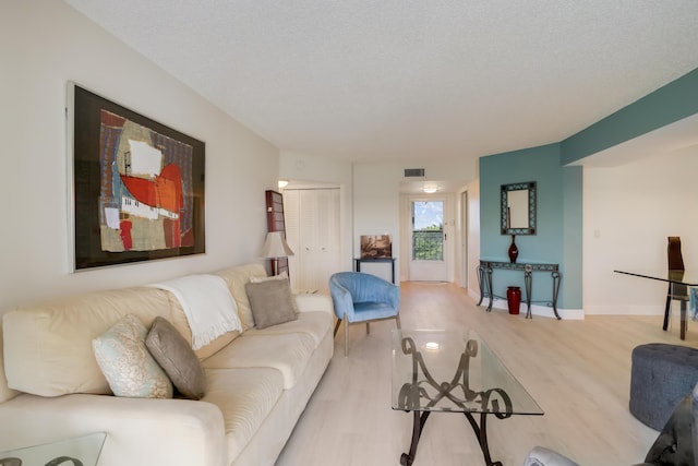 living room featuring light wood-type flooring, baseboards, and visible vents