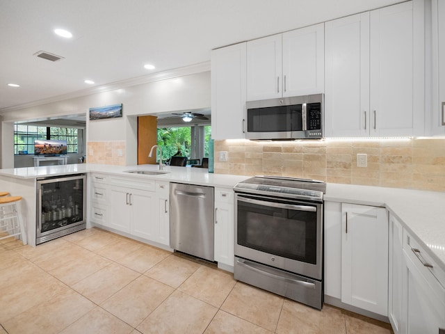 kitchen featuring white cabinets, sink, beverage cooler, appliances with stainless steel finishes, and crown molding