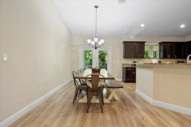 dining area with light wood-type flooring, french doors, and a notable chandelier