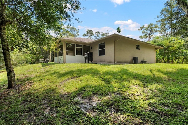 back of property with a lawn and a sunroom