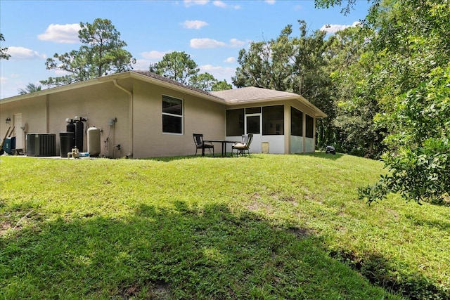 rear view of house with a sunroom, a yard, and central air condition unit