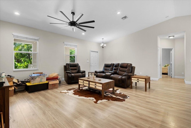 living room with ceiling fan with notable chandelier, light wood-type flooring, lofted ceiling, and a wealth of natural light