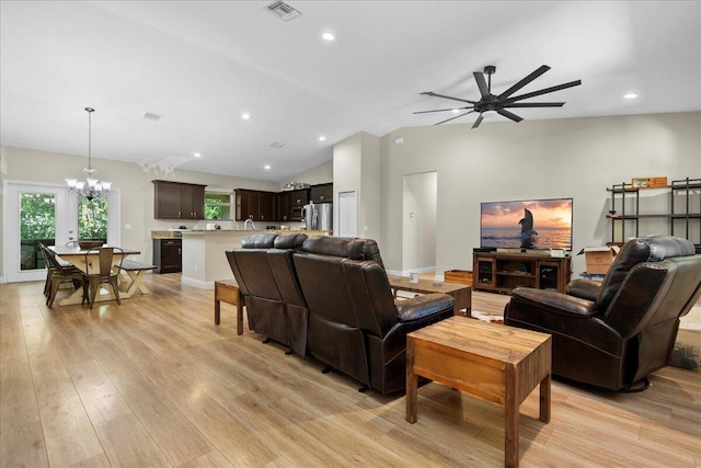 living room featuring light wood-type flooring, ceiling fan with notable chandelier, and vaulted ceiling