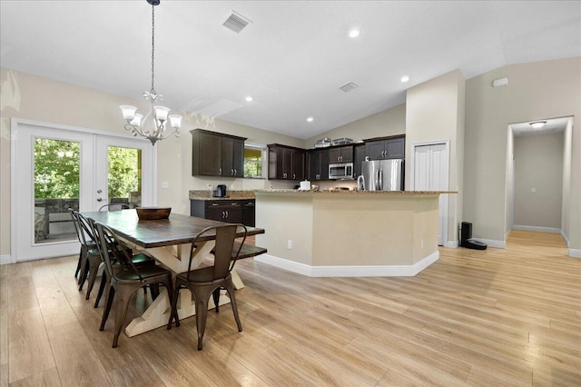 dining space with an inviting chandelier, light wood-type flooring, vaulted ceiling, and french doors