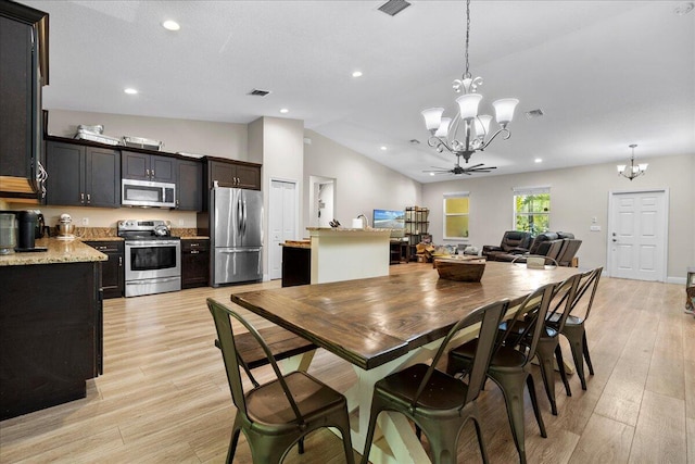 dining room featuring ceiling fan with notable chandelier, vaulted ceiling, and light hardwood / wood-style floors