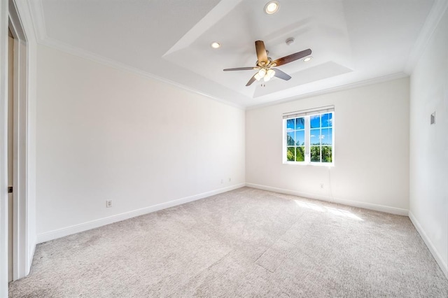 carpeted empty room featuring ornamental molding, ceiling fan, and a tray ceiling