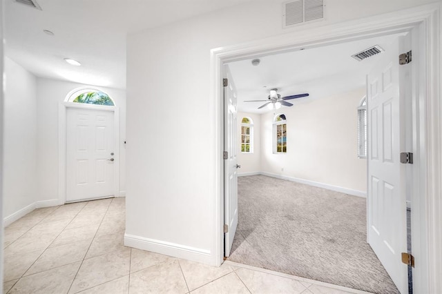 foyer entrance featuring ceiling fan, a healthy amount of sunlight, and light carpet