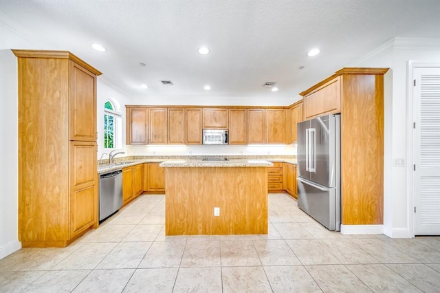 kitchen with sink, light stone counters, a center island, ornamental molding, and appliances with stainless steel finishes