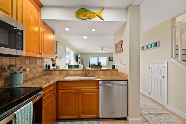 kitchen featuring tasteful backsplash, sink, stone counters, stainless steel appliances, and ceiling fan