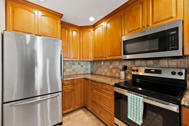 kitchen with light stone countertops, appliances with stainless steel finishes, backsplash, and light tile patterned floors