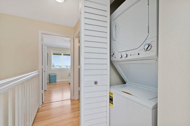 laundry area with light wood-type flooring and stacked washer and dryer