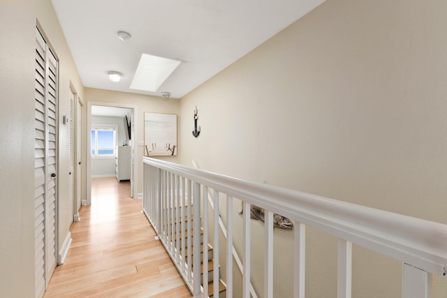 hallway featuring a skylight and light hardwood / wood-style flooring